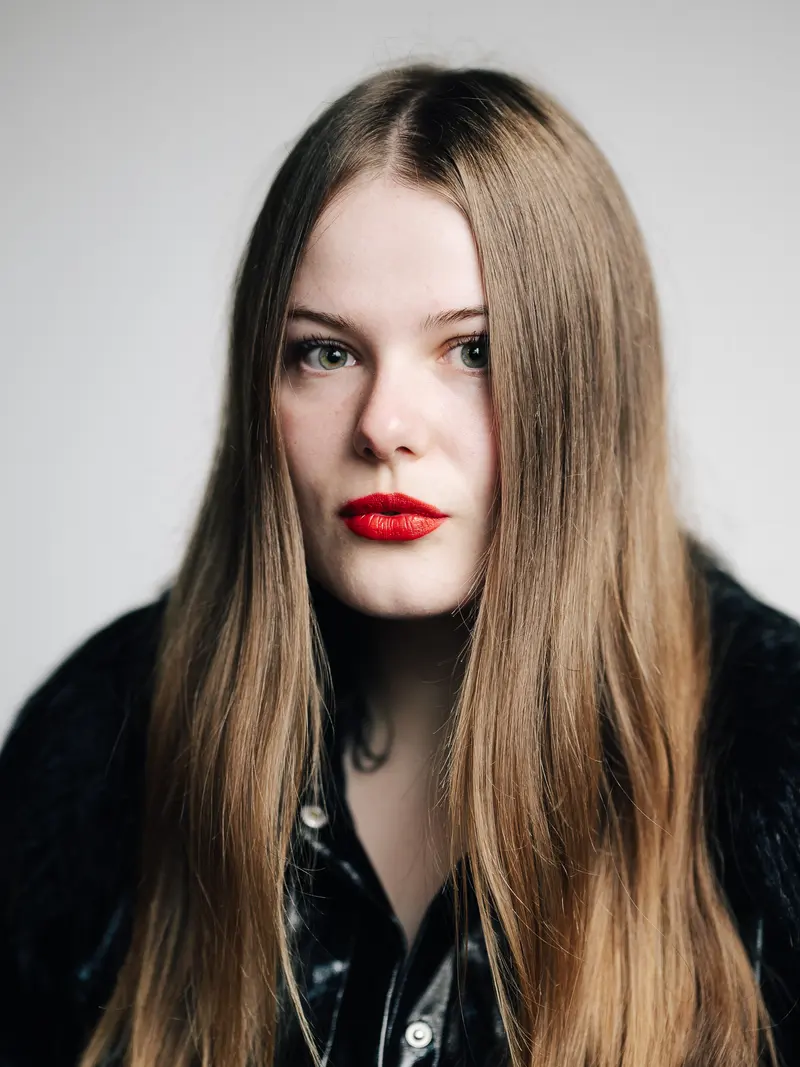 Porträt von Merle Friede mit rotem Lippenstift vor hellem Hintergrund